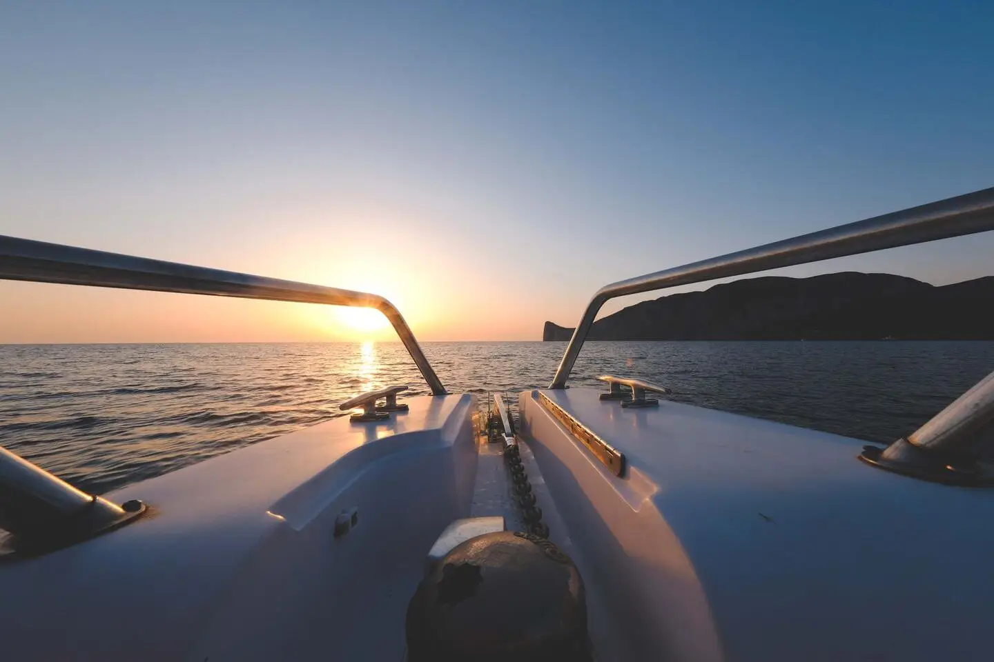 View over the bow rail and cleats of a yacht at sunset off the Riviera coast